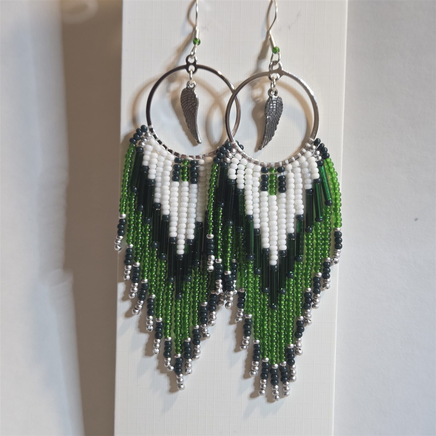 Green, black, and white handmade beaded feather hoop earrings